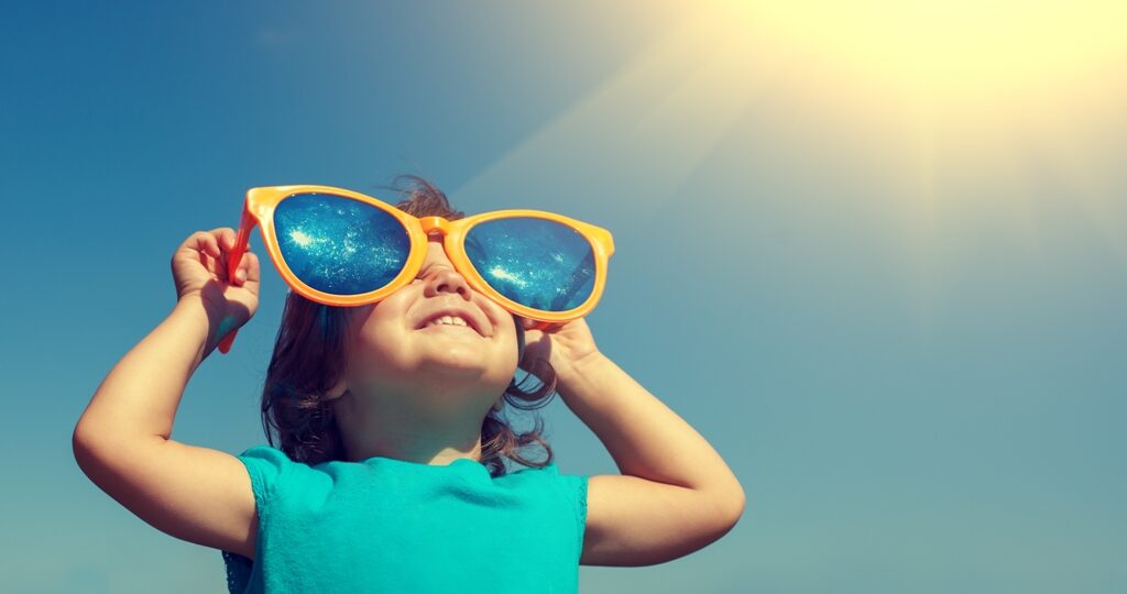 Happy little girl with big sunglasses  looking at the sun