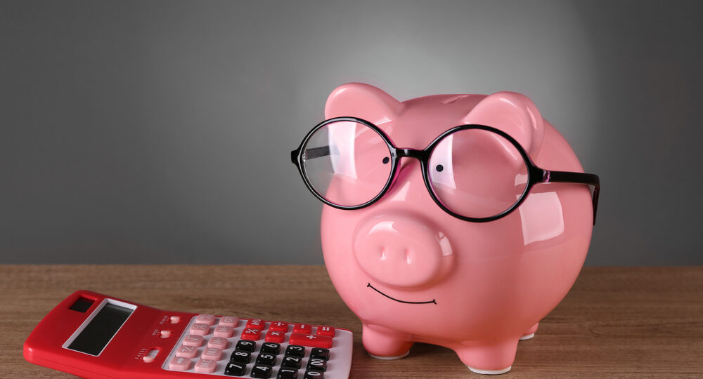 Piggy,Bank,In,Glasses,With,Calculator,On,Grey,Background